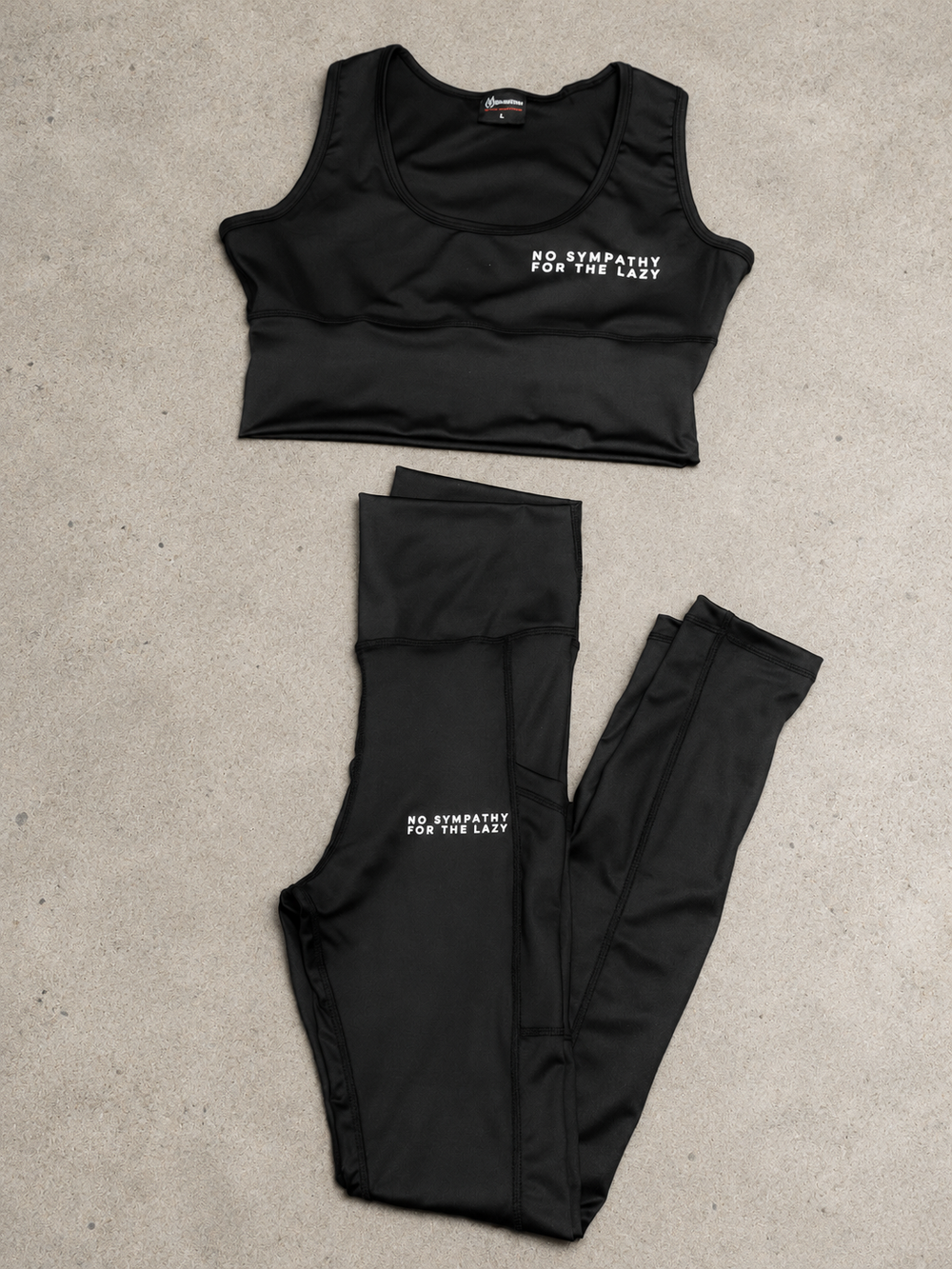 Black NSV-L sports bra and leggings set laid flat on stone